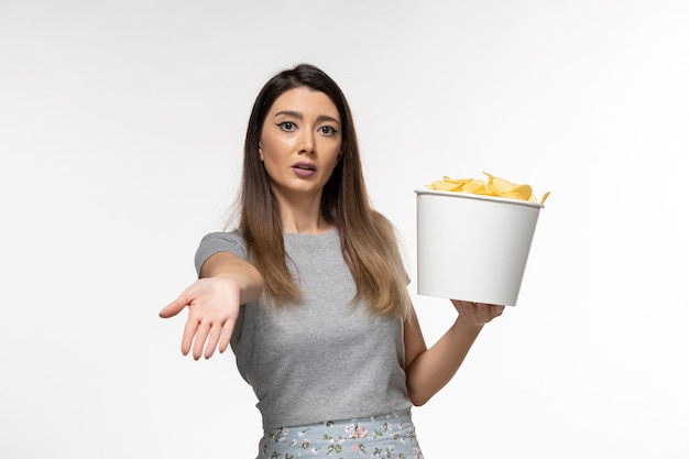 Free photo front view young female holding chips while watching movie on white surface