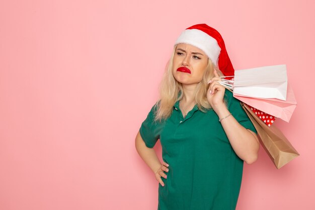 Front view young female holding christmas presents in packages on pink wall model xmas new year photo color