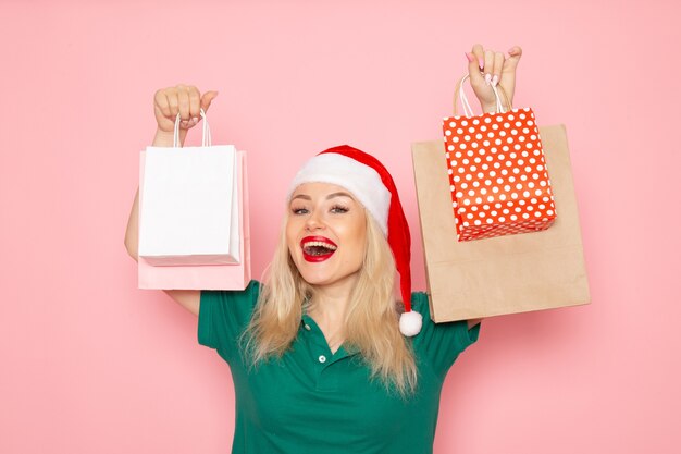ピンクの壁にパッケージでクリスマスプレゼントを保持している正面図若い女性クリスマス写真モデル年末年始
