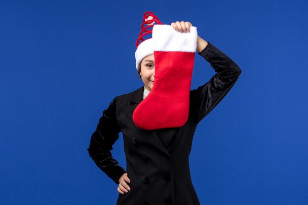 Вид спереди молодая женщина держит рождественский носок на синем столе праздничная женщина новый год