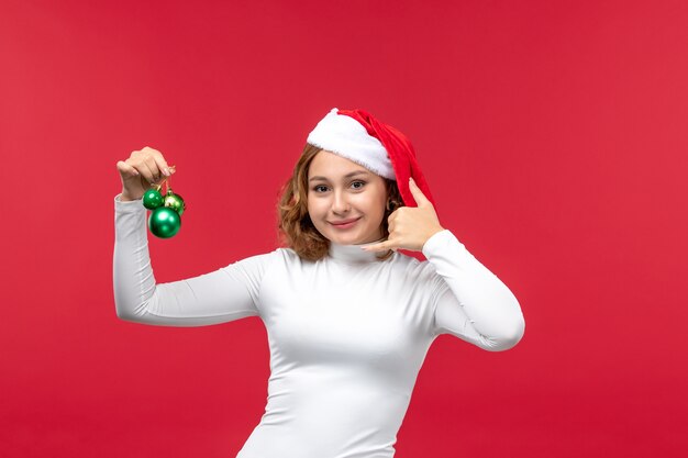 赤でクリスマスのおもちゃを保持している若い女性の正面図