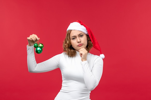 Вид спереди молодой женщины, держащей рождественские игрушки на красном