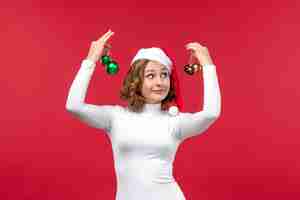 Free photo front view of young female holding christmas toys on red