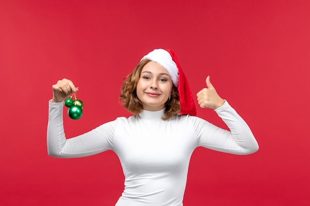 Front view of young female holding christmas toys on red