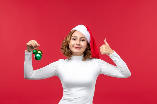 Вид спереди молодой женщины, держащей рождественские игрушки на красном