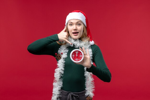 Front view young female holding clock on a red background