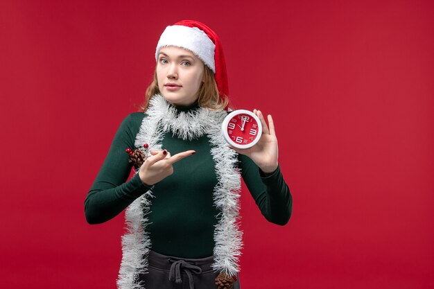 Front view young female holding clock on a red background