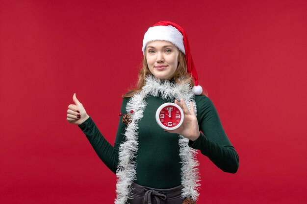 Free photo front view young female holding clock on red background