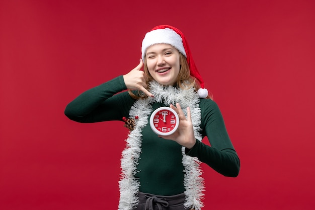 Front view young female holding clock on red background