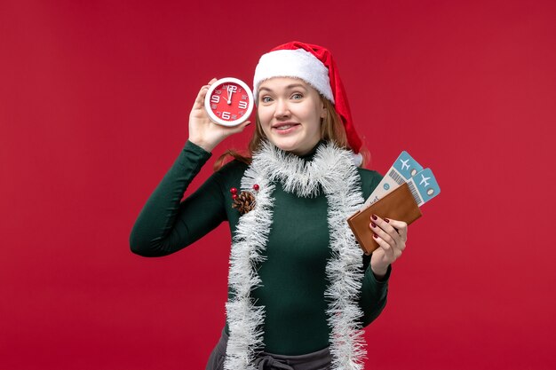 Front view young female holding clock and tickets on a red background