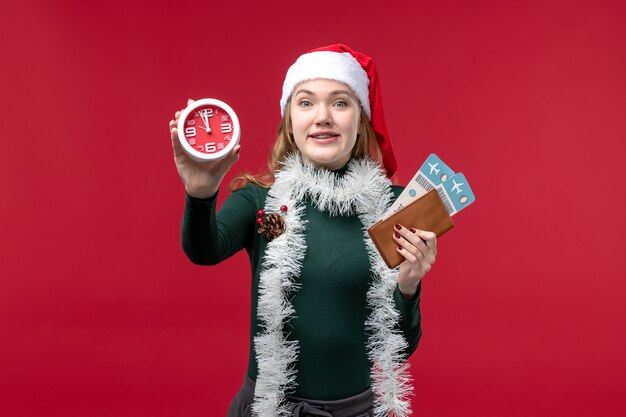 Front view young female holding clock and tickets on red background