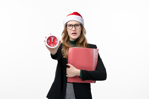 ファイルと白い壁の本の新年のクリスマスの時計を保持している若い女性の正面図
