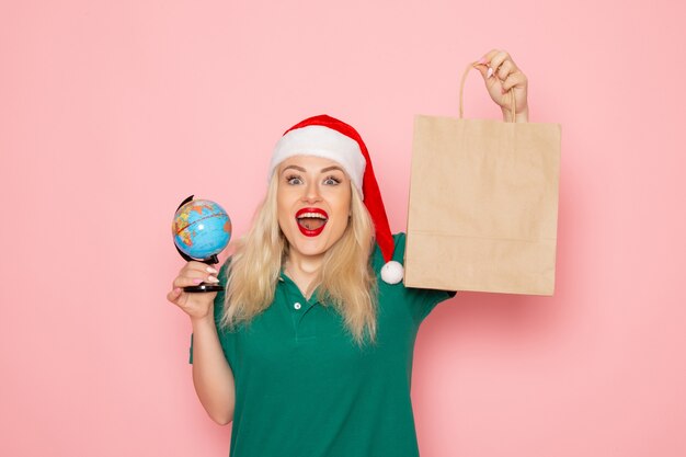 Front view young female holding globe and christmas present on pink wall model woman xmas new year holiday