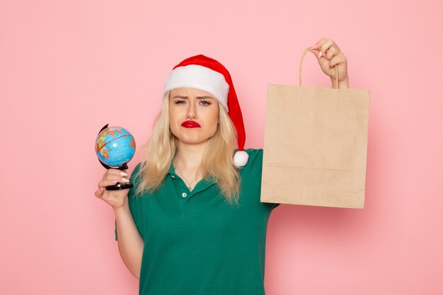 Front view young female holding globe and christmas present on pink wall xmas photo model woman new year holidays