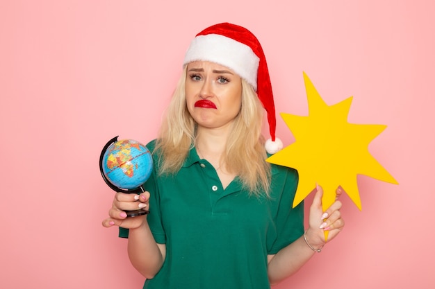 Front view young female holding globe and yellow figure on pink wall model woman holiday 