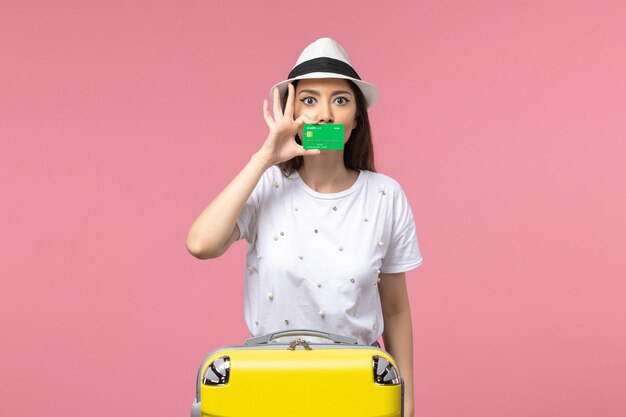 Front view young female holding green bank card on pink wall emotions summer woman trip