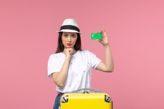Front view young female holding green bank card on a pink wall emotions woman trip summer