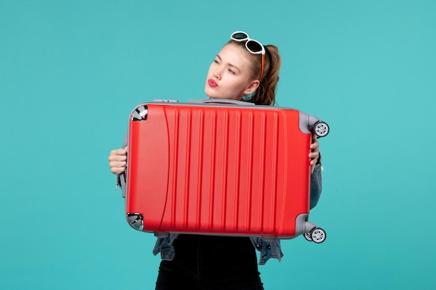 Front view young female holding her red bag and preparing for trip on blue space