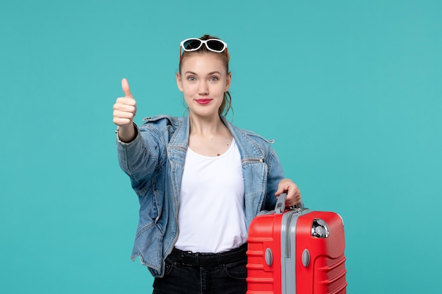 彼女の赤いバッグを保持し、水色の空間で旅行の準備をしている正面図若い女性