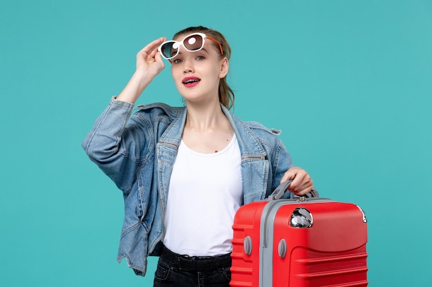 Front view young female holding her red bag and preparing for trip on a light blue space