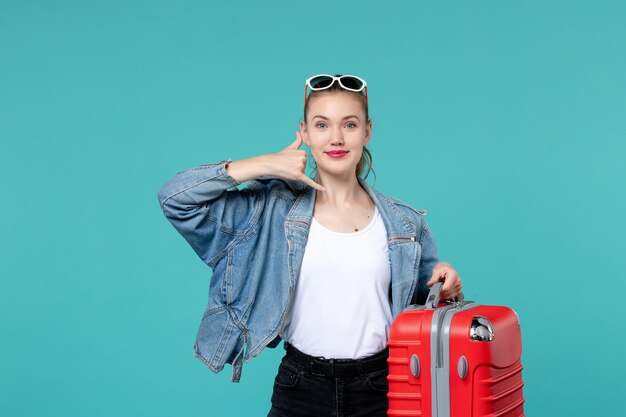 Front view young female holding her red bag and preparing for trip smiling on blue space