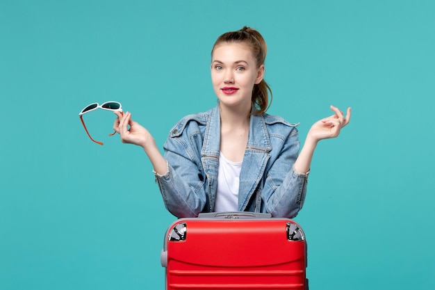 Front view young female holding her sunglasses preparing for vacation on a blue space