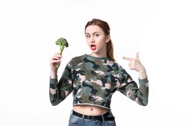 Вид спереди молодая женщина держит маленькую брокколи на белом фоне еда диета салат блюдо тело обед еда здоровье