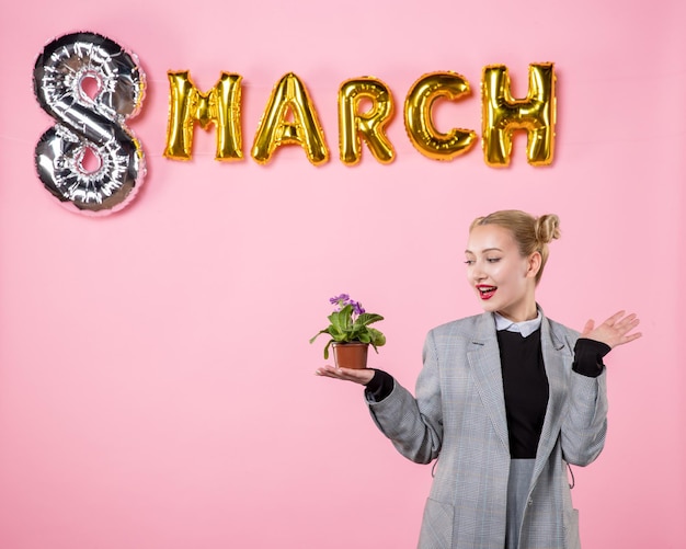 분홍색 배경 파티 관능적 인 수평 여성 여성의 날 평등 색상에 3 월 장식으로 작은 꽃을 들고 전면 보기 젊은 여성