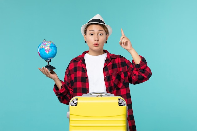 Foto gratuita giovane femmina di vista frontale che tiene piccolo globo sullo spazio azzurro