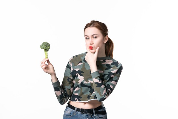 Front view young female holding little green broccoli and thinking on white background salad meal diet horizontal health dish body food lunch