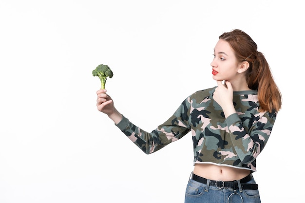 Vista frontale giovane femmina che tiene piccoli broccoli verdi su sfondo bianco corpo dieta insalata pasto salute piatto cibo pranzo orizzontale
