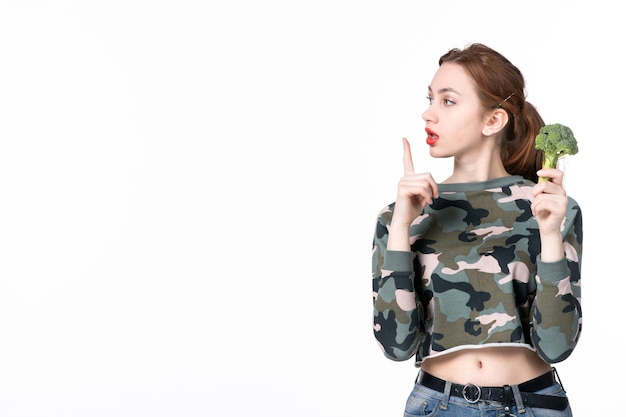 Front view young female holding little green broccoli on white background meal salad dish lunch human weight healthcare diet food