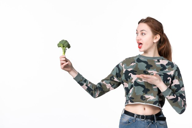 Front view young female holding little green broccoli on white background salad lunch meal diet health dish body horizontal