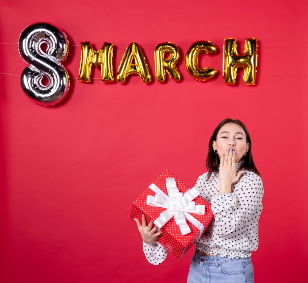 Front view young female holding march present and sending kisses on red background horizontal equality woman feminine affectionate shopping beauty holiday love