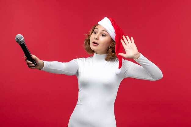 Front view of young female holding mic on red