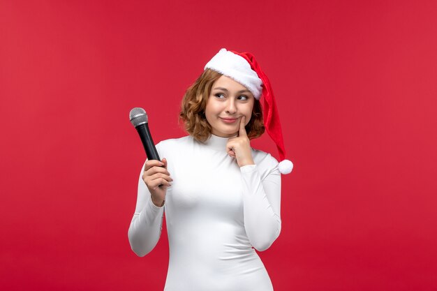 Front view of young female holding mic on red