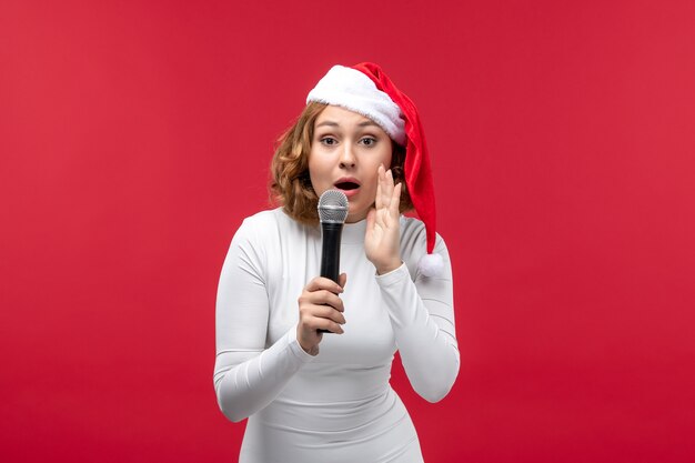 Front view of young female holding mic on red