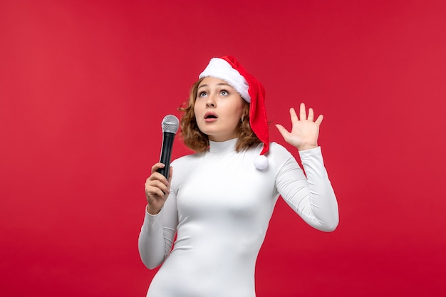 Front view of young female holding mic on red