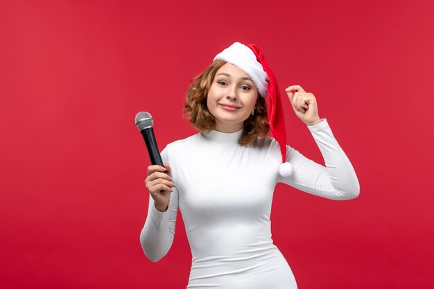 Вид спереди молодой женщины, держащей микрофон на красном