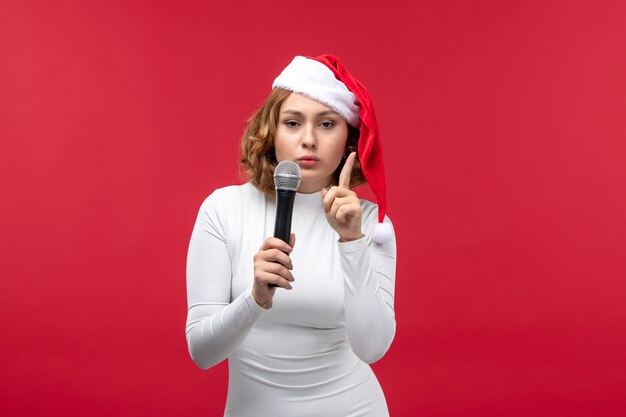 Front view of young female holding mic on red