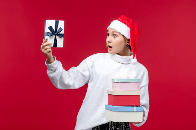 Front view young female holding new year presents on red background