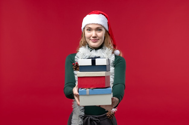 Front view young female holding new year presents on a red background