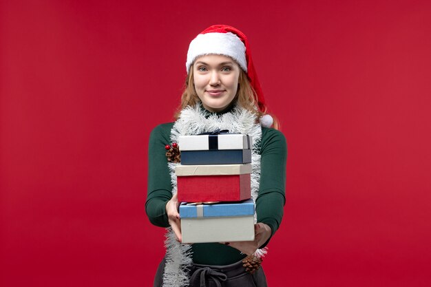 Front view young female holding new year presents on a red background