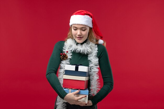 Front view young female holding new year presents on red desk