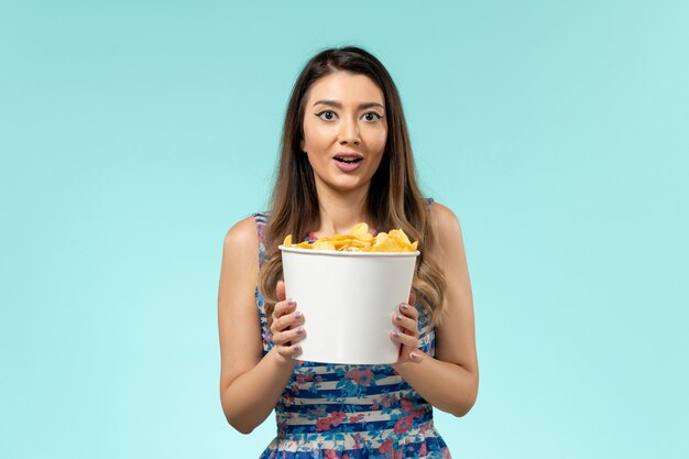 Front view young female holding package with chips on blue surface