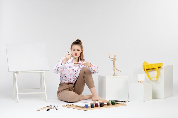 Front view young female holding paints for drawing on a white background