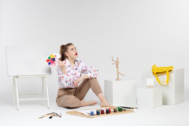 Front view young female holding paints for drawing on white background