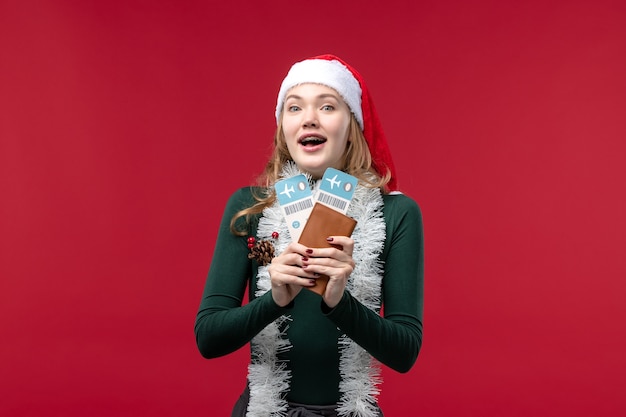 Front view young female holding plane tickets on a red background