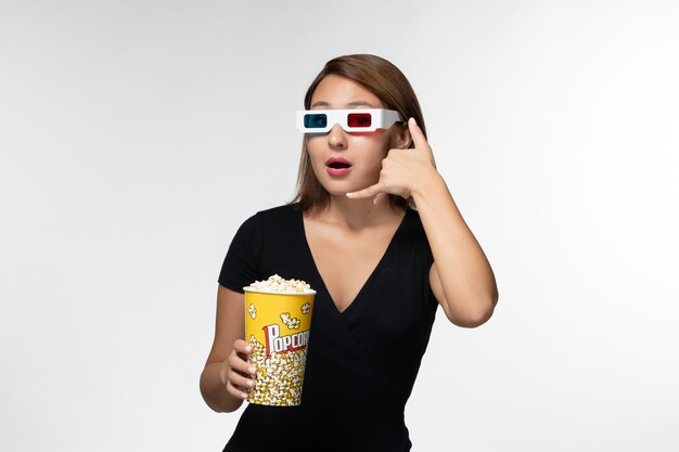 Front view young female holding popcorn in d sunglasses posing on white surface