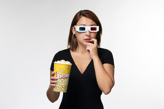 Front view young female holding popcorn package in d sunglasses on white surface